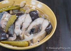 a yellow bowl filled with mushrooms and pickles on top of a black tablecloth