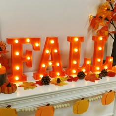 the word fall is lit up with candles and pumpkins