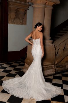 a woman in a white wedding dress standing on a checkered floor with her back to the camera