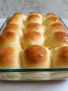 a casserole dish filled with rolls on top of a white tablecloth covered counter