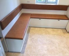 a corner bench with storage underneath it in a room that has tile flooring and white walls