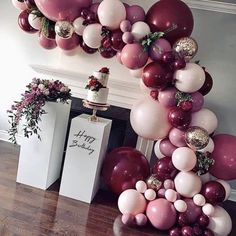 a bunch of balloons that are on the ground in front of a cake and some flowers