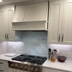 a stove top oven sitting inside of a kitchen next to white cabinets and counter tops