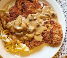 a white plate topped with meat patties covered in gravy next to macaroni and cheese