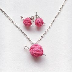 two pink balls of yarn are attached to silver chain necklace and earring pendants