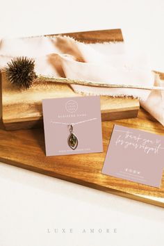 two necklaces sitting on top of a wooden tray next to other jewelry and papers