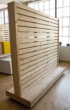 a wooden bench sitting on top of a hard wood floor next to large windows in an office building