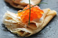 an appetizer with orange beads on top of tortilla shells and garnishes