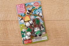 a package of panda eraser toys sitting on top of a wooden table next to a tree