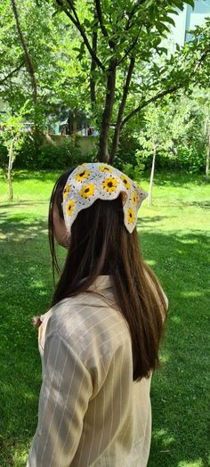 a woman standing in the grass with her back to the camera, wearing a sunflower headband