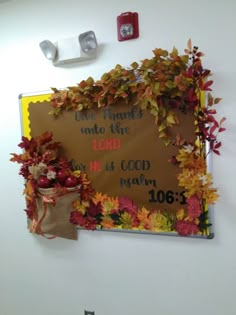 a bulletin board with fall leaves on it and a bag hanging from the wall next to it