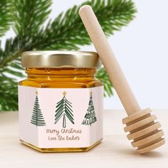 a jar of honey with a wooden spoon next to it and christmas trees on the label