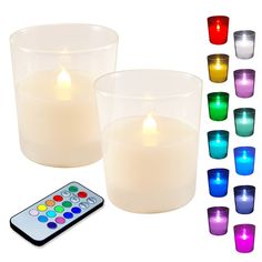 two lit candles with remote controls in front of each candle and several different colored cups