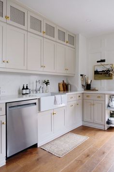 a clean kitchen with white cabinets and wood flooring, including a dishwasher