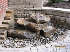 an outdoor fountain with rocks and water coming from it