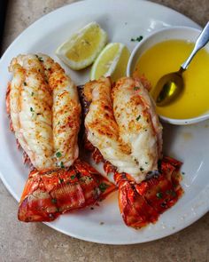 lobsters on a plate with dipping sauce and lemon wedges