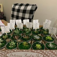 there are many potted plants on display in the table with cards attached to them