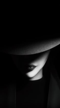 black and white photograph of a woman's face wearing a hat in the dark