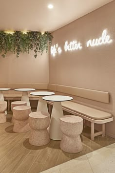 the interior of a restaurant with round tables and stools, plants growing on the wall