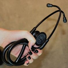 a person holding a stethoscope in their right hand and wearing black nail polish