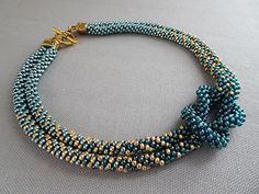 a blue and gold beaded necklace on a white surface