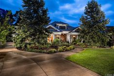 a large house with lots of trees in the front yard and landscaping around it at night