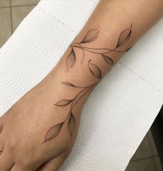 a woman's foot with leaves on it and a tattoo design on the toe