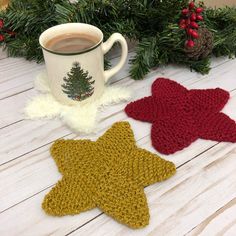 two crocheted star coasters sitting next to a cup of coffee