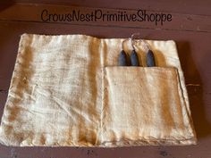 three knives are in the pocket of an old cloth bag that says crowe nest primitives shoppe