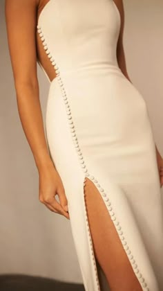 a woman wearing a white dress with a slit through the side