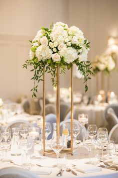 a tall centerpiece with white flowers and greenery