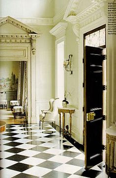 an elegant living room with black and white checkerboard flooring, chandelier, mirror, table and chairs