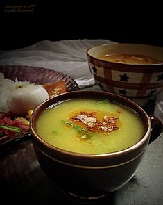 two bowls filled with soup sitting on top of a table next to other food items