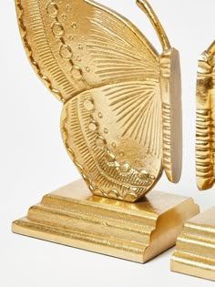 a gold butterfly figurine sitting on top of two pieces of wood and metal