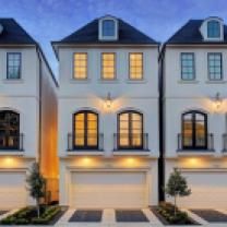 three story white house with black roof and windows at night time in front of blue sky