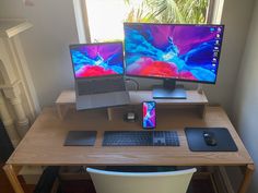 two computer monitors sitting on top of a wooden desk