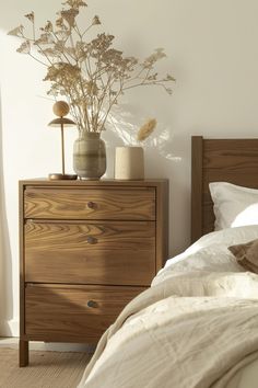 a bed room with a neatly made bed and a vase on top of the dresser