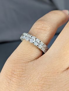 a woman's hand with a diamond ring on her left hand and the other hand holding an engagement band