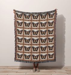 a woman standing in front of a wall holding up a blanket with butterflies on it