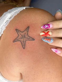 a woman's belly with a starfish tattoo on her stomach and colorful nails