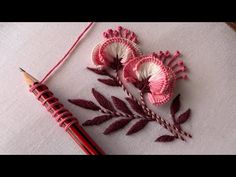 a crocheted flower and pencil rest on a piece of white fabric next to a needle