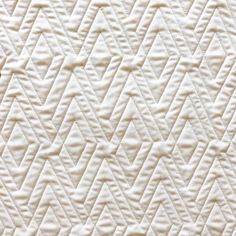 an up close view of a quilted material with white stitching on the edges