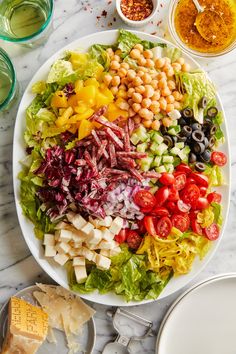 a large salad on a plate with dressings around it