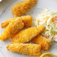 fried fish with coleslaw and slaw on a white plate next to a lemon wedge