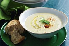 a bowl of soup with bread on a green plate