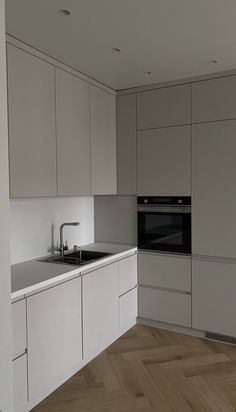 an empty kitchen with white cabinets and wood flooring