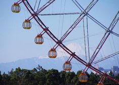 a ferris wheel with some lights hanging from it's sides and mountains in the background