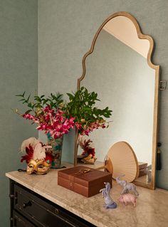 there is a mirror and some flowers on the dresser