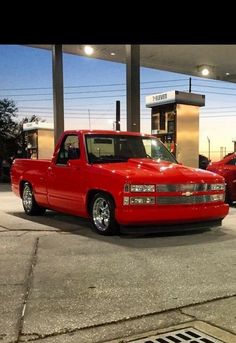 a red truck parked in front of a gas station