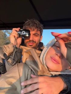 a man and woman taking a selfie in the back of a car with their camera